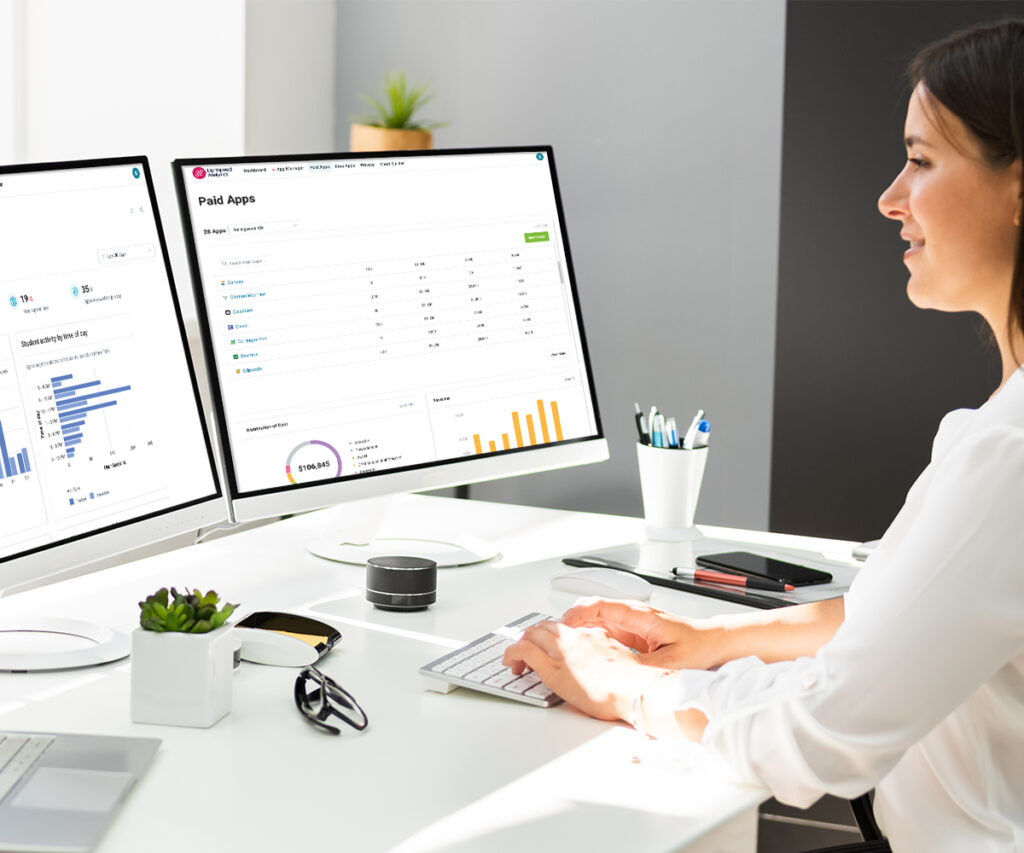 Woman sitting at desk typing on two desktop monitor computers