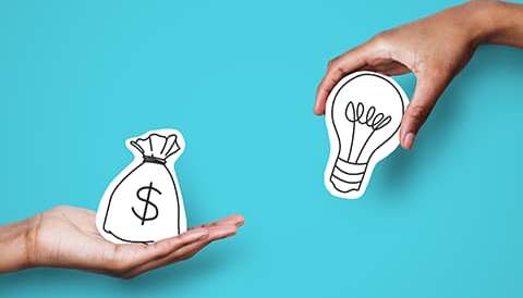 Two hands, one holding light bulb and other holding money icon
